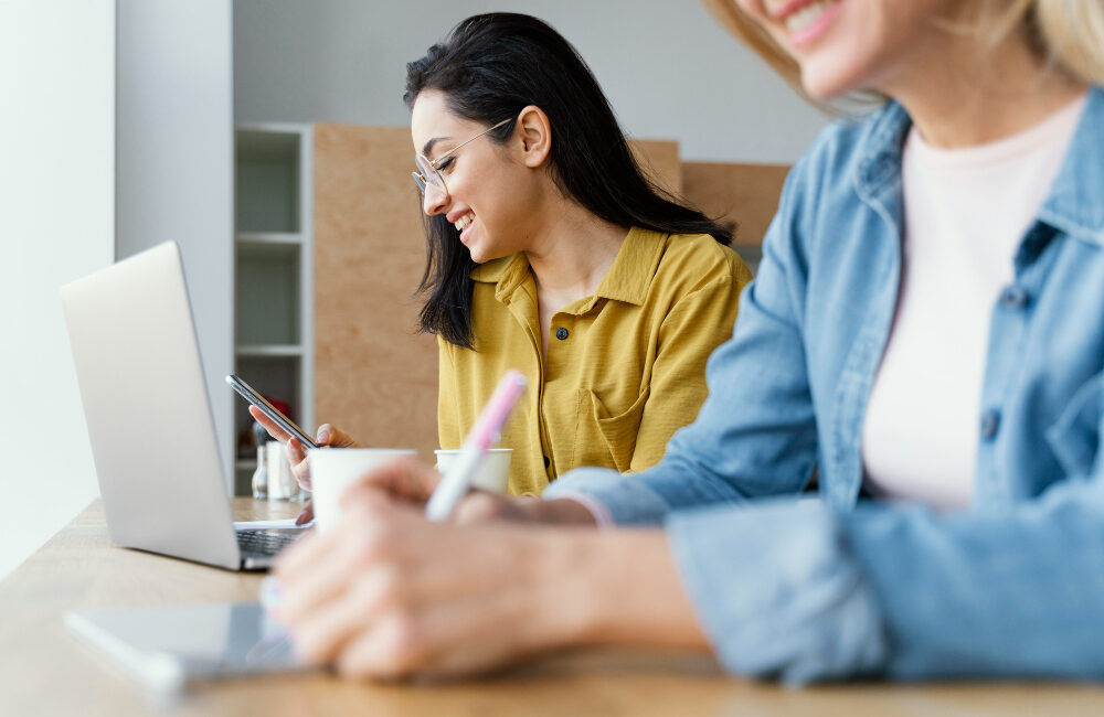 Zwei Frauen sitzen am Laptop bei einer digitalen Arbeitsschutzschulung.