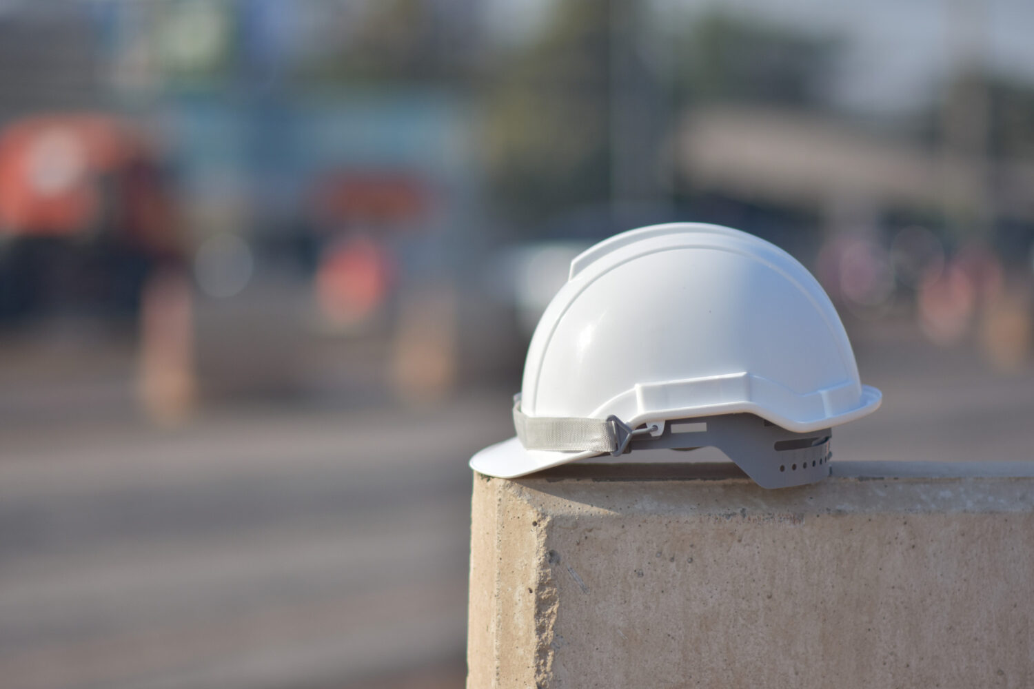 Ein weißer Arbeitsschutzhelm liegt auf einer Betonmauer