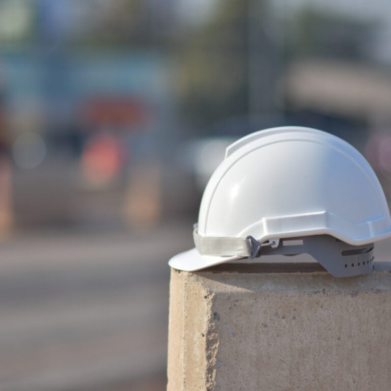 Ein weißer Arbeitsschutzhelm liegt auf einer Betonmauer