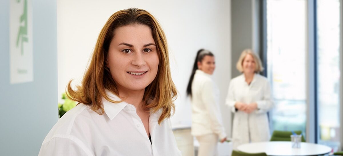 Eine Mitarbeiterin eins Employee Assistance Programmes steht in einem Raum mit anderen Mitarbeitenden.