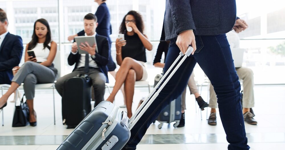 Geschäftsreisender mit Rollkoffer am Flughafen.