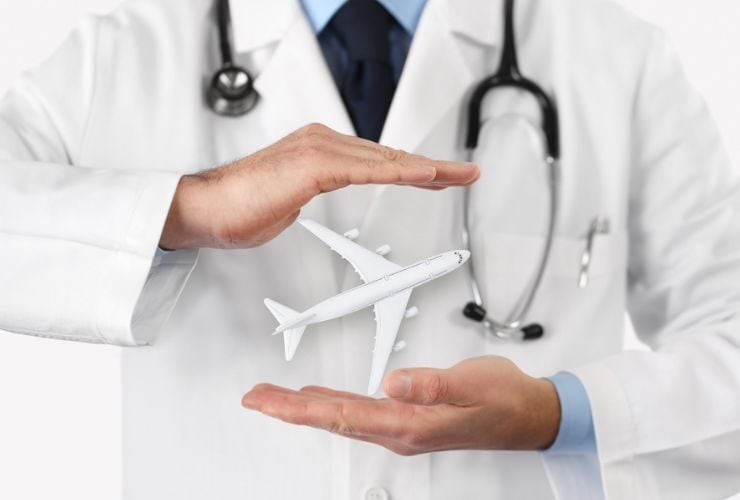 Ein Symbolbild für Reisemedizin. Ein Arzt mit einem Modellflugzeug in den Händen.