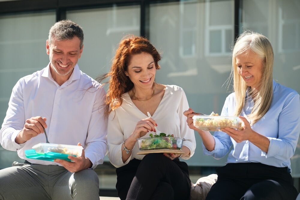 Mitarbeitende essen draußen gemeinsam zu Mittag.