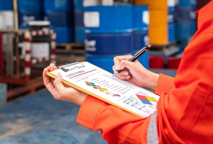 Eine Person in Arbeitskleidung füllt einen Fragebogen zu Gefahrstoffen im Unternehmen aus.
