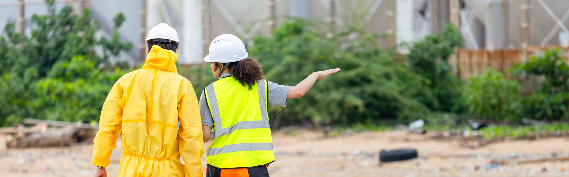 Ein SiGeKo und ein Mitarbeitender stehen auf einer Außenbaustelle und besprechen sich.